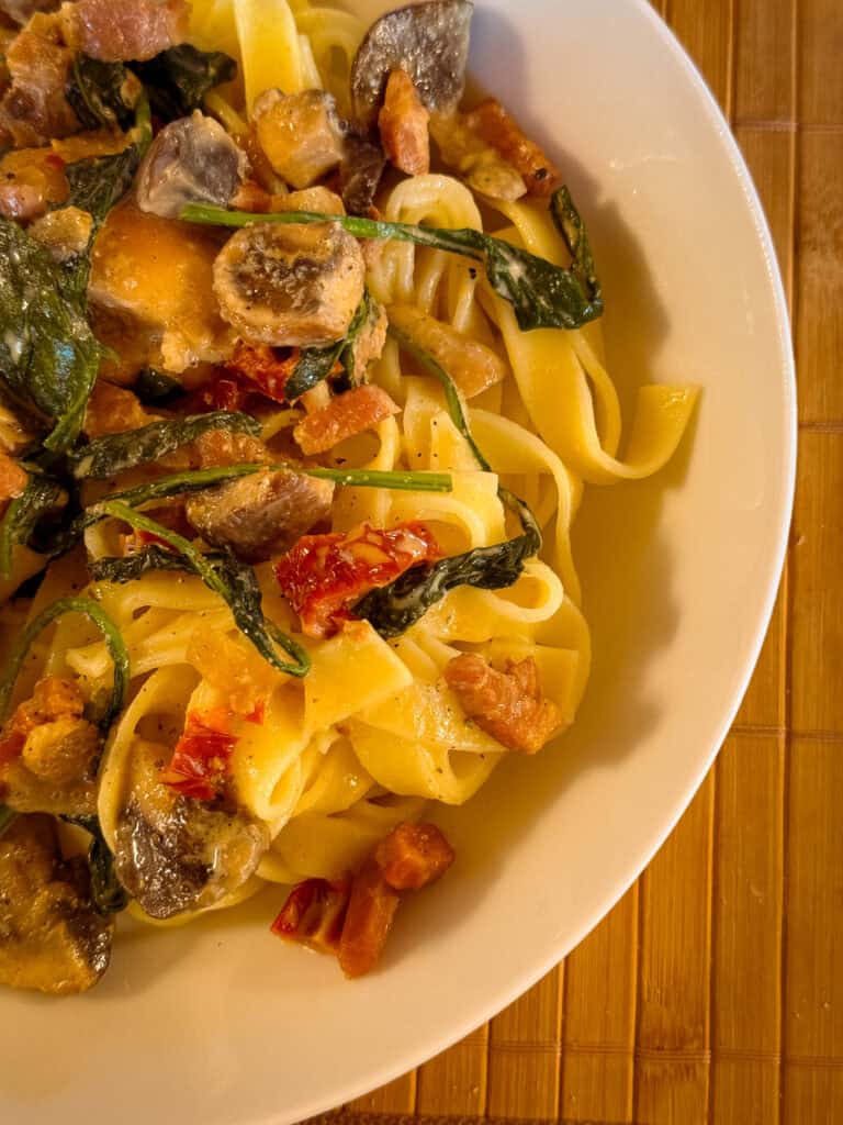 Pasta mit Hähnchenbrustfilet getrockneten Tomaten Pilzen und Blattspinat