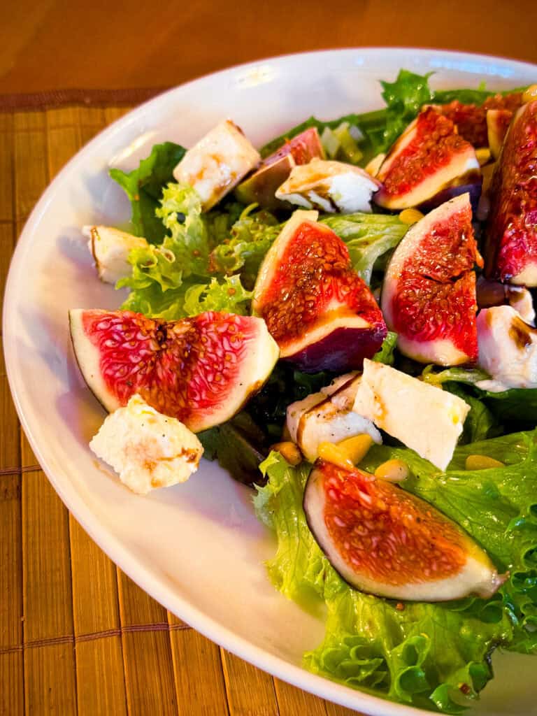 Feigen mit Mozzarella und Pinienkernen auf einem Salatbett